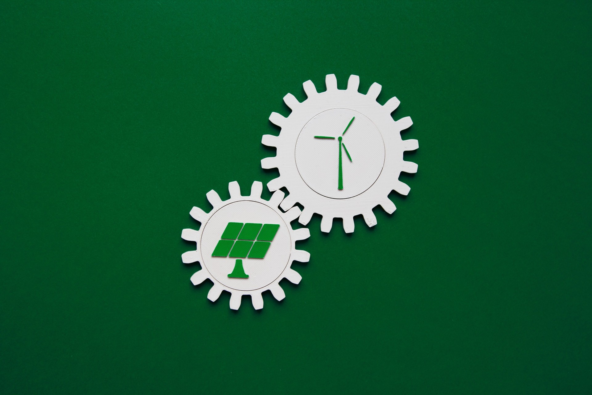 Interlocking gear wheels with wind turbine and solar panel icons on green background